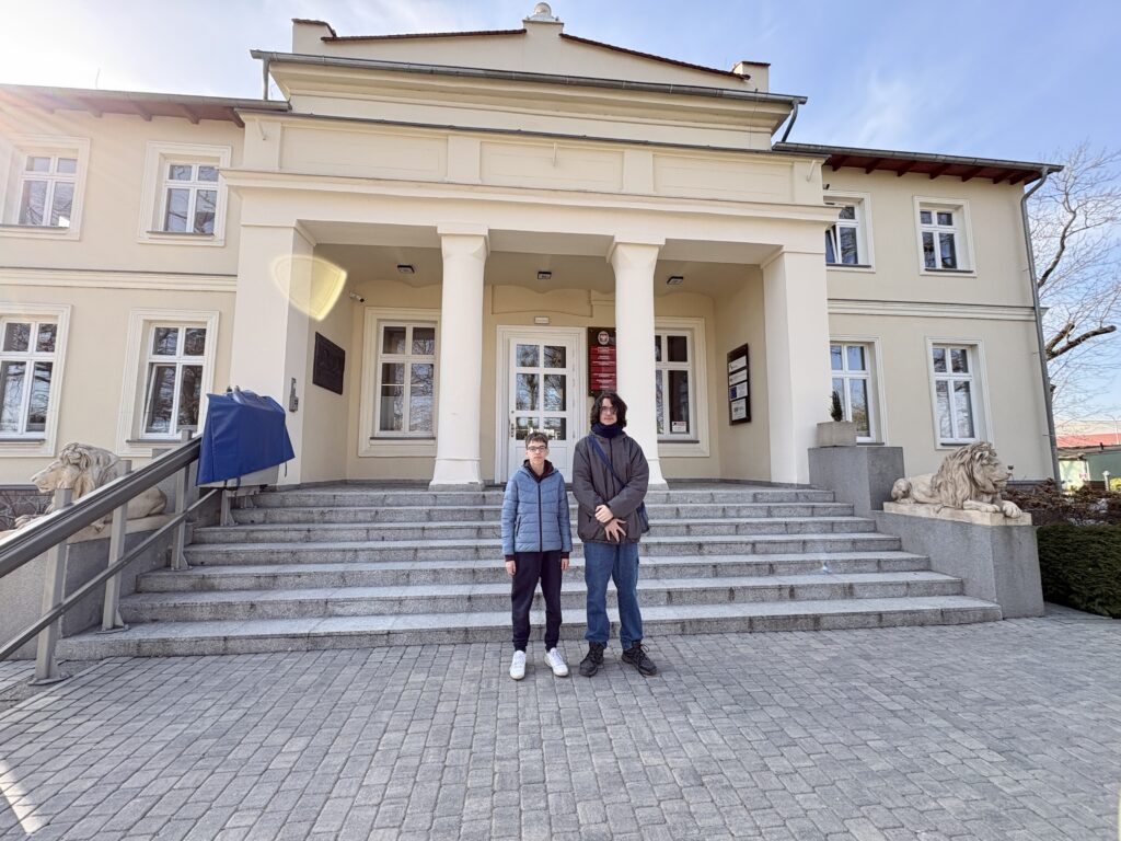 Uczniowie stoją przed budynkiem szkoły w Rokietnicy