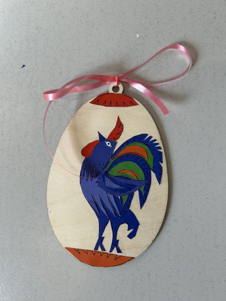 ozdoba świąteczna-drewniany kształt jajka, na nim przyklejony kolorowy kogucik