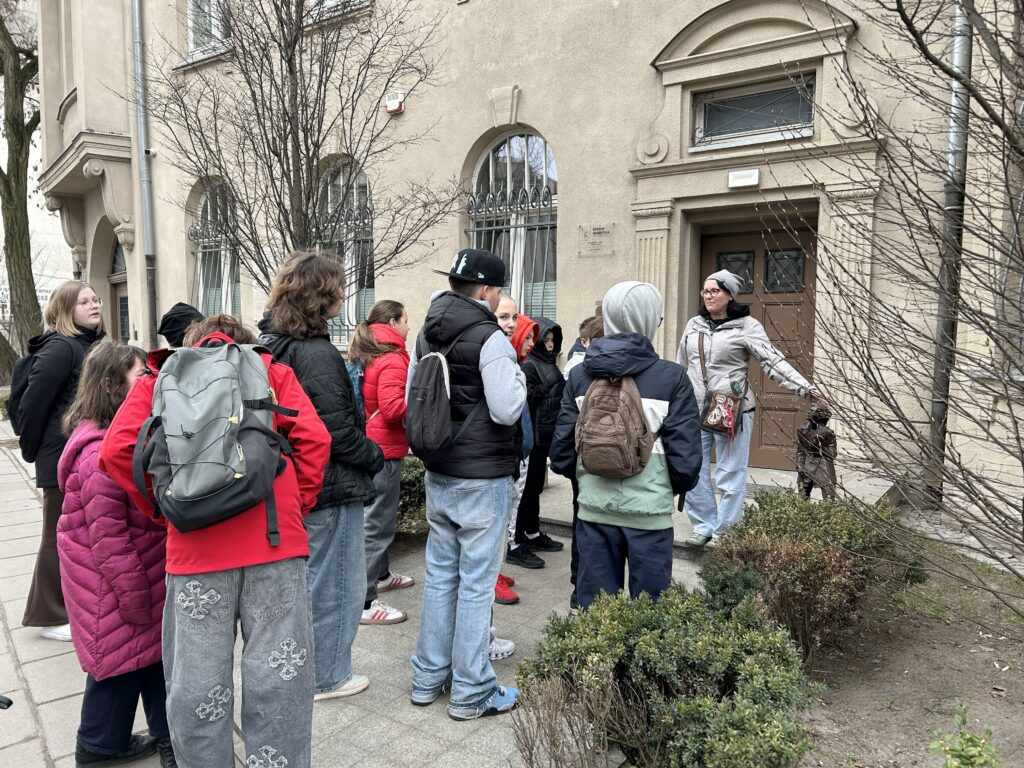 uczniowie stoją przed budynkiem na ul. Wólczańskiej i podziwiają rzeźbę krasnala Olo z filmu Kingsajz