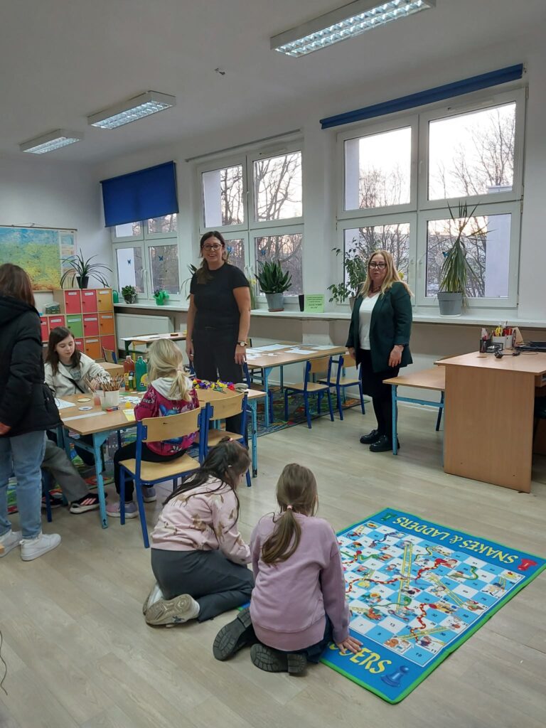 dzieci bawią się w sali, część na dywanie