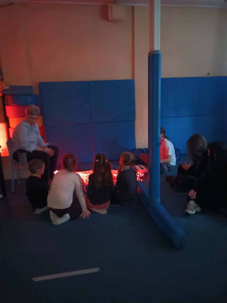 pani coś tłumaczy dzieciom w sali terapeutycznej 