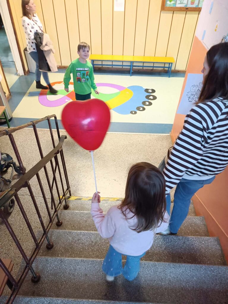dziecko schodzi ze schodów z mamą trzymając balona