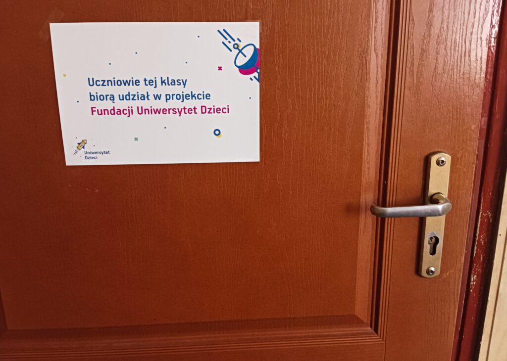 zdjęcie drzwi i napisu uczniowie tej klasy biorą udział w projekcie Fundacji Uniwersytet Dzieci