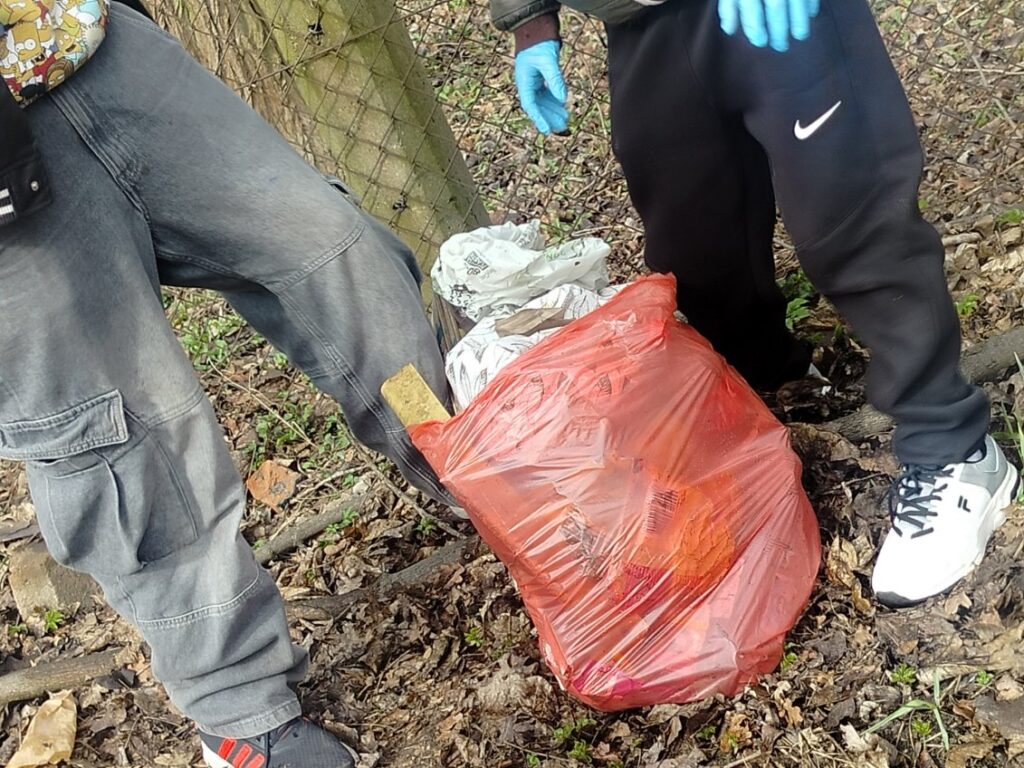 na zdjęciu widzimy nogi uczniów i worek pełen śmieci