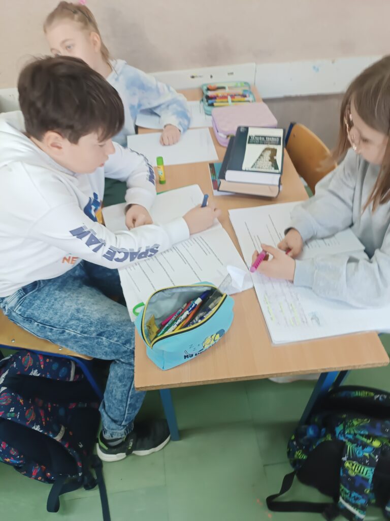 uczeń i uczennice rozwiązują zadania, siedzą w ławkach