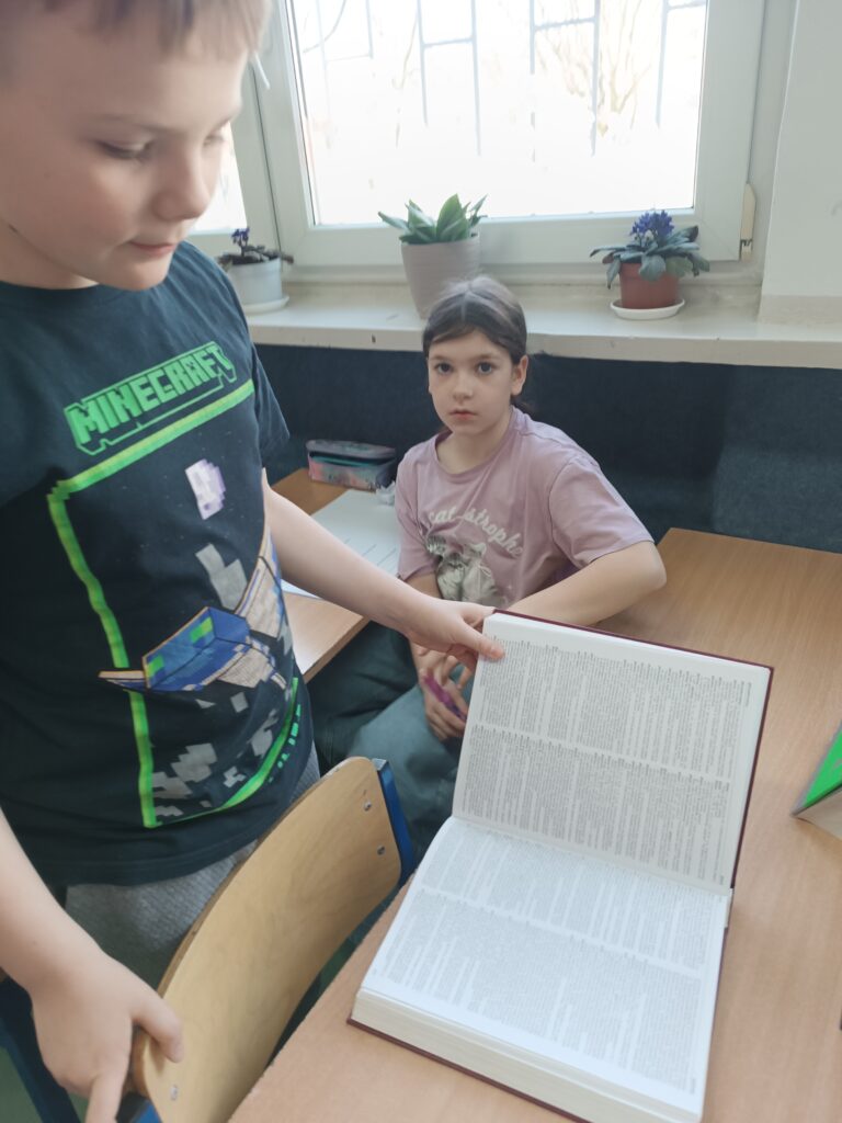 uczeń i uczennica rozwiązują zadania, uczeń trzyma książkę 