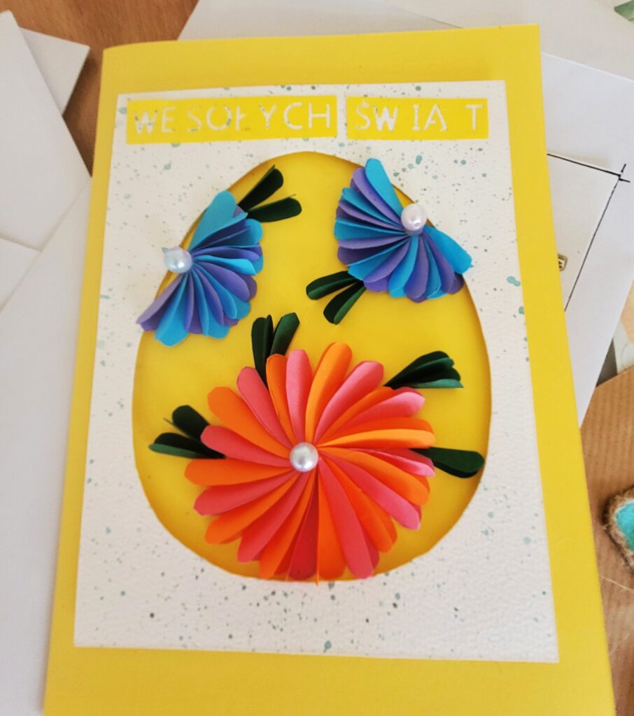 Kartka wielkanocna wykonana z kolorowego papieru, przedstawiająca jajko w kwiaty.