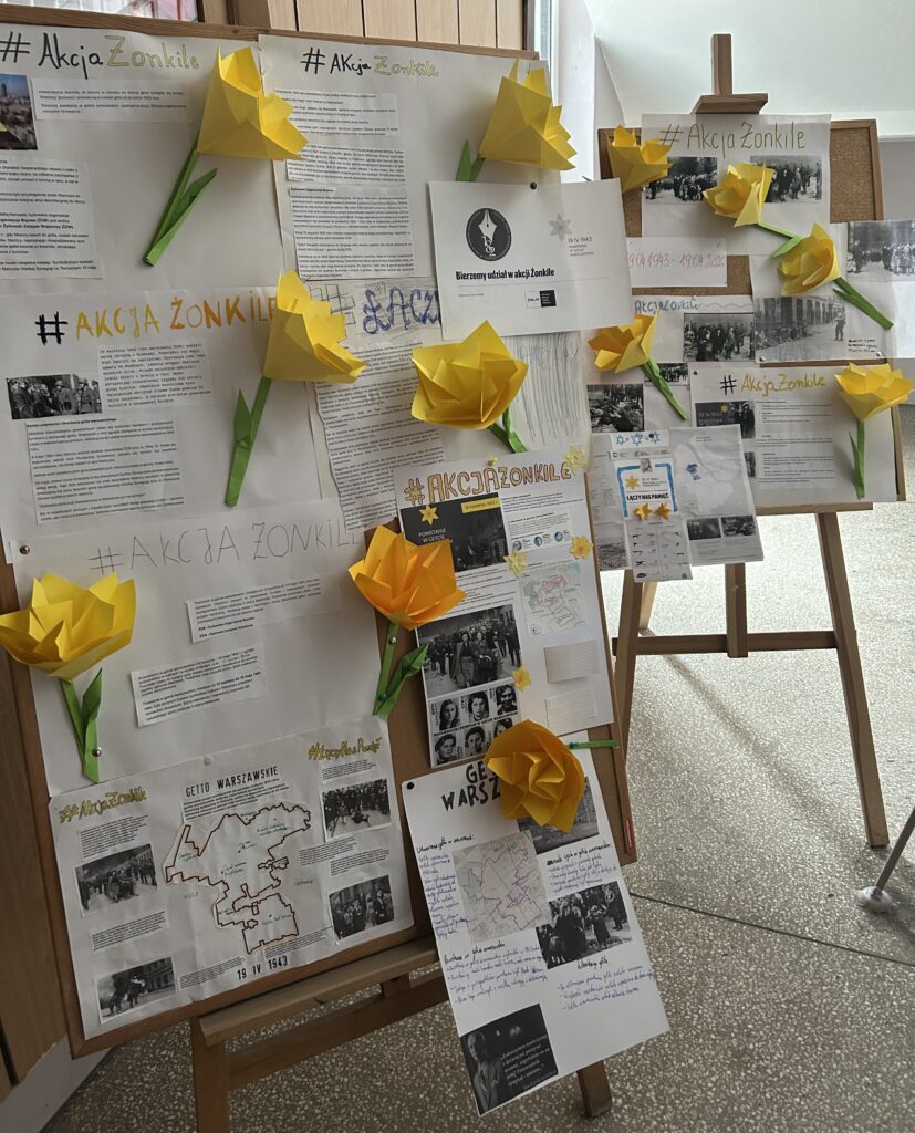 na zdjęciu widać plakaty które dzieci przygotowały, upamietniają powstanie w getcie warszawskim i akcję Żonkile. Do plakatów przyczepione są żółte kwiaty, które dzieci wykonały z papieru