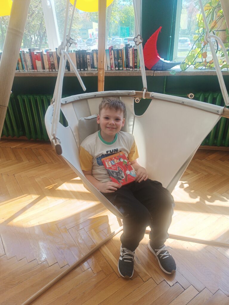 uczeń siedzi w fotelu i trzyma książkę 