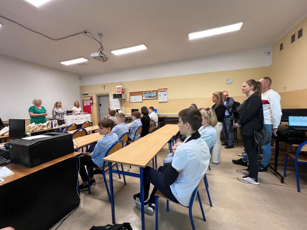 troje nauczycieli w tym pani Dyrektor przemawiają, widać nagrody i osoby od tyłu ich słuchających