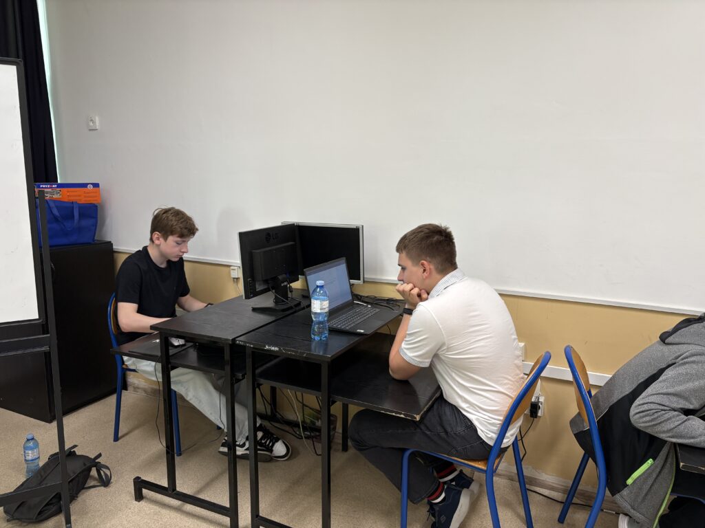 dwoje uczniów, każdy siedzi przy swoim stanowisku komputerowym i rozwiązuje test na komputerze