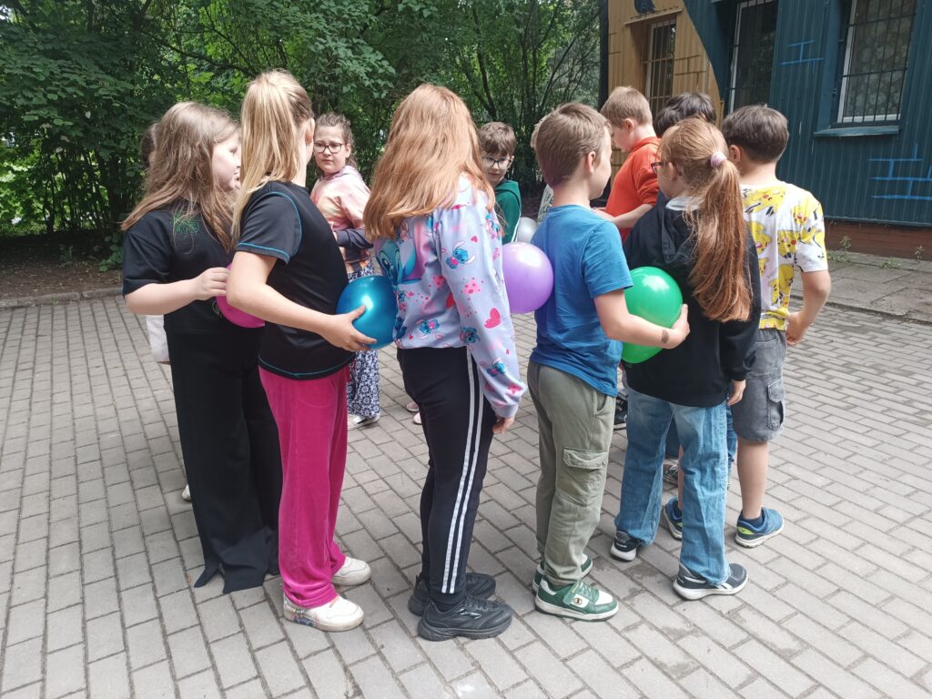 dzieci trzymają balony stoją w kole jedno za drugim