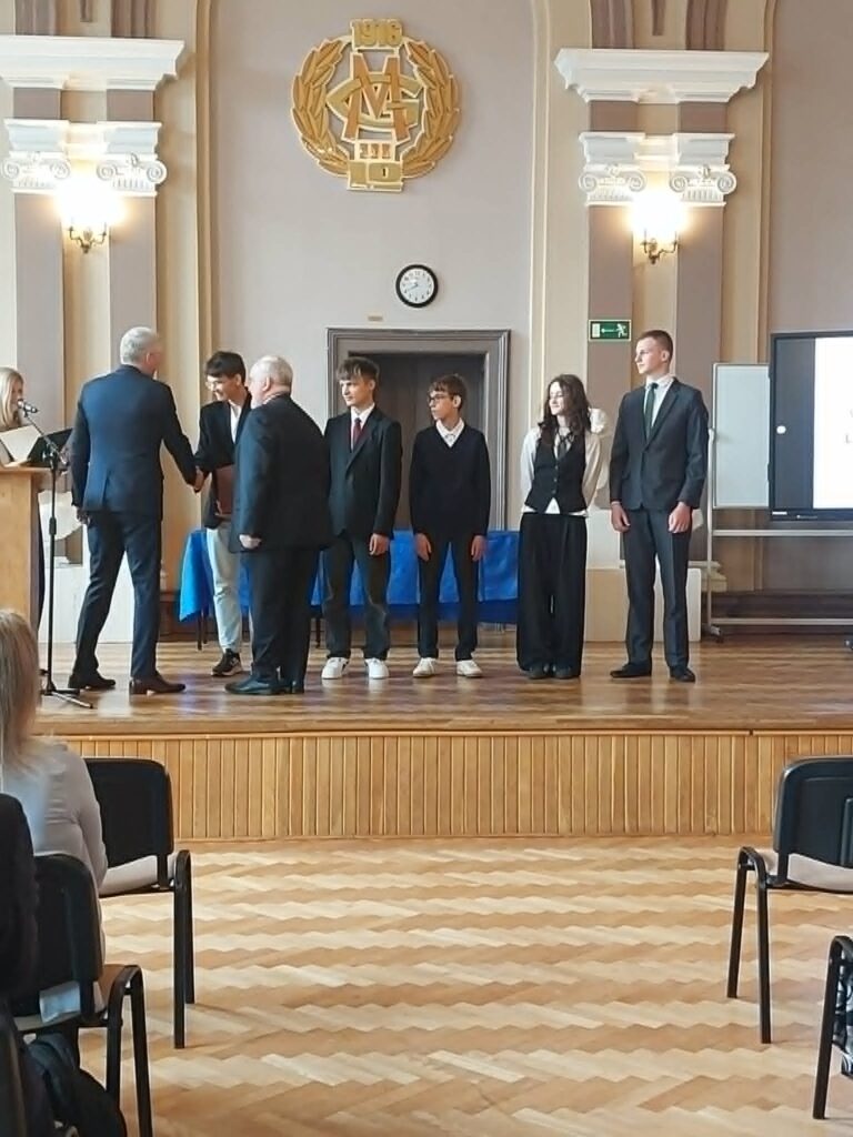uczniowie stoją , dwóch panów składa im gratulacje