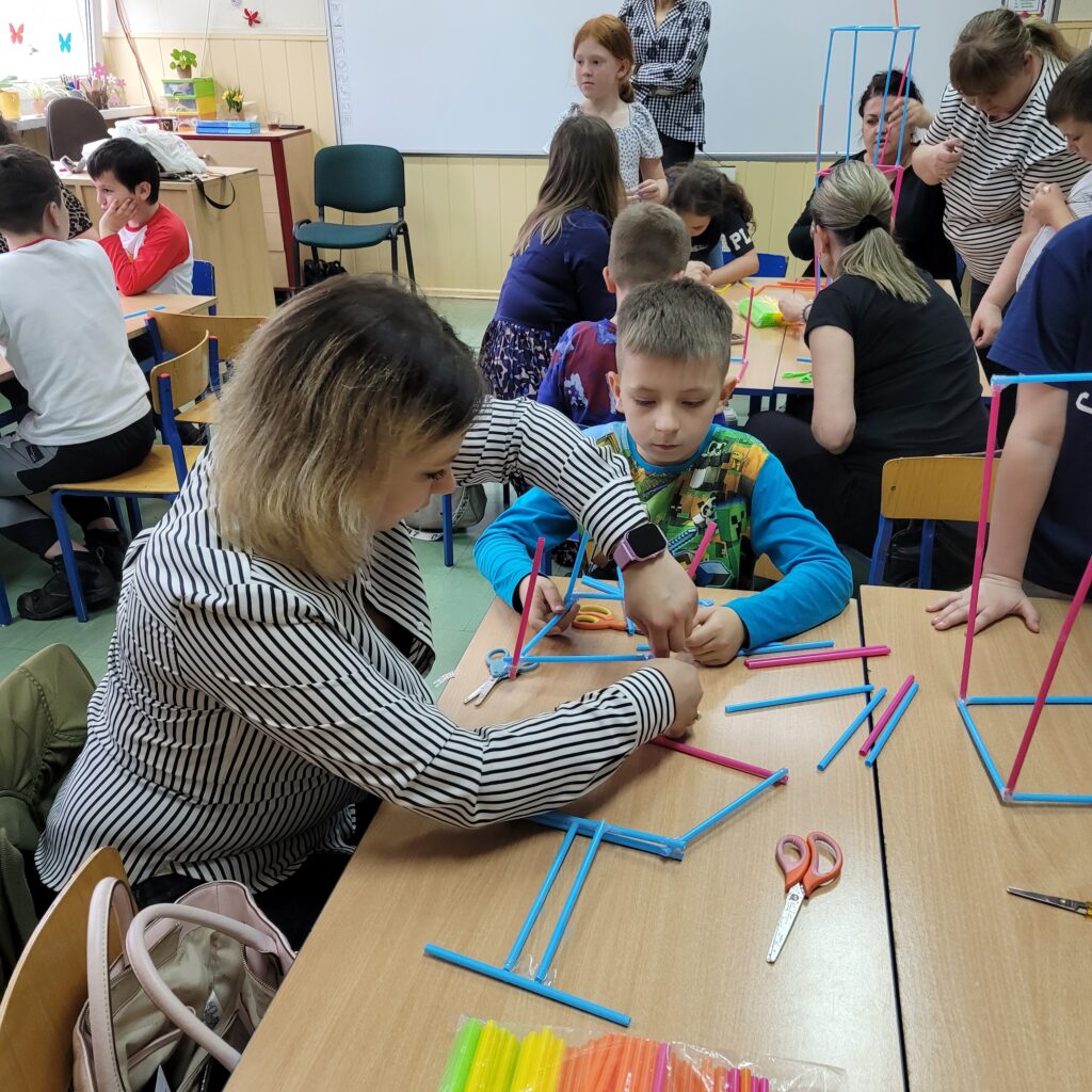 dzieci i rodzice budują razem ze słomek specjalnych kolorowych do łączenia