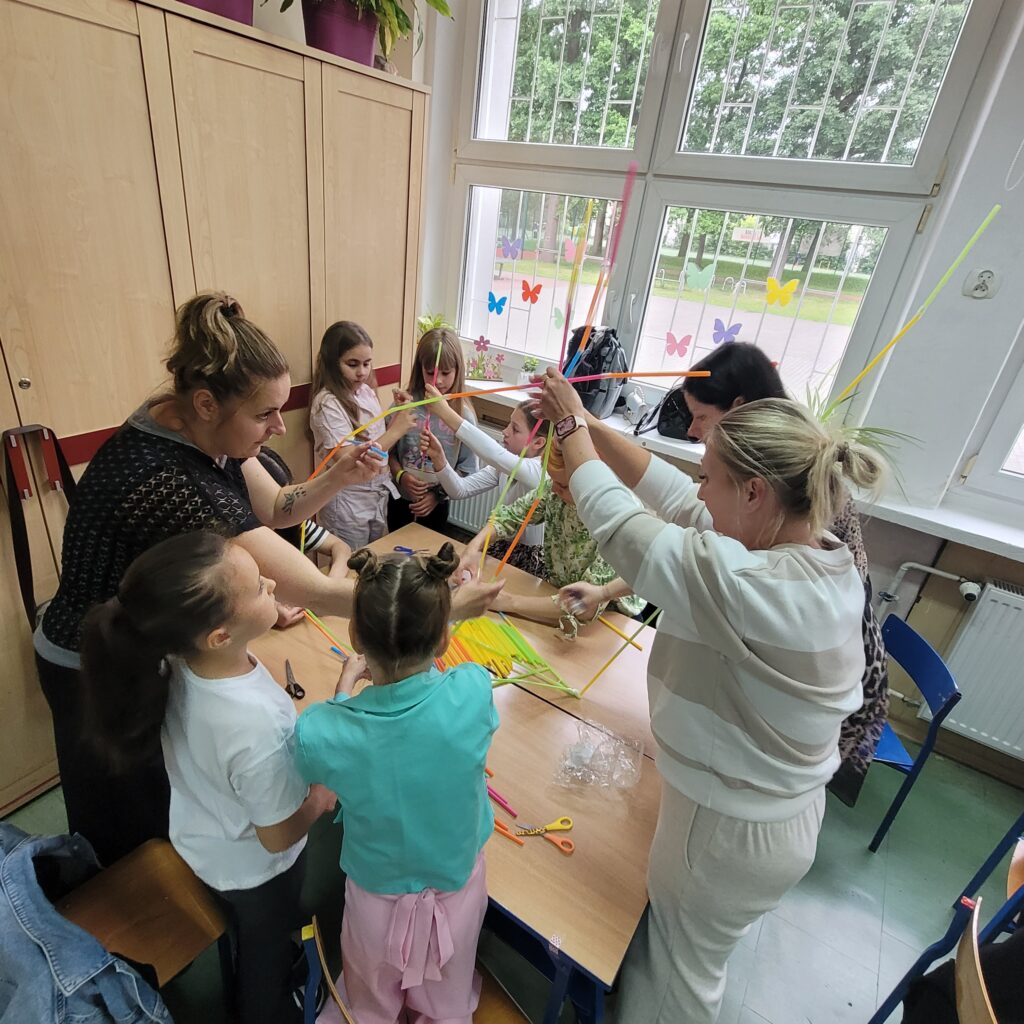 dzieci i rodzice budują razem ze słomek specjalnych kolorowych do łączenia