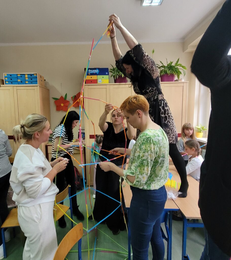 dzieci i rodzice budują razem ze słomek specjalnych kolorowych do łączenia