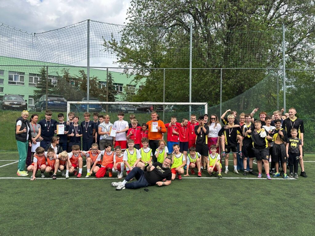 zdjęcie grupowe wszystkich zawodnikach w kolorowych koszulkach, z nauczycielami