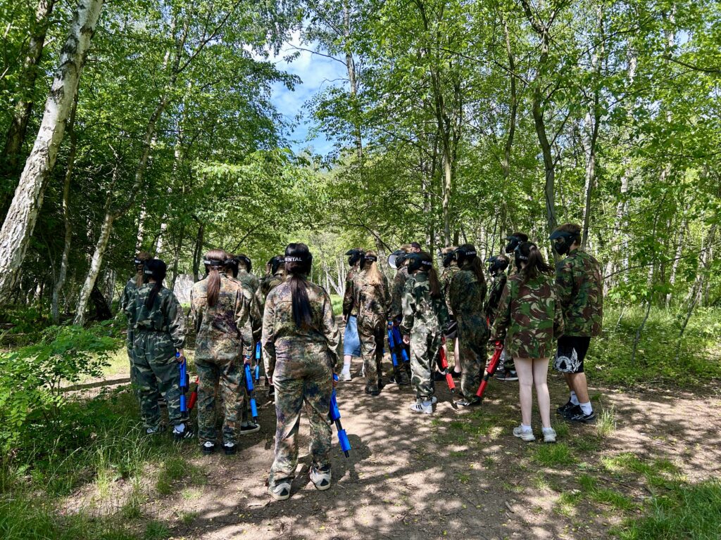 uczniowie stoją tyłem do aparatu w strojach z pistoletami w klorze czerwonym i niebieskim
