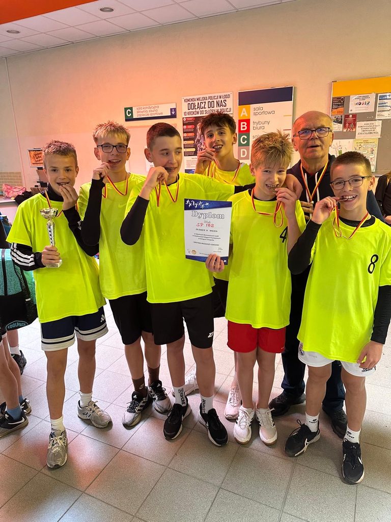 uczniowie pozują wraz z nauczycielem z medalami