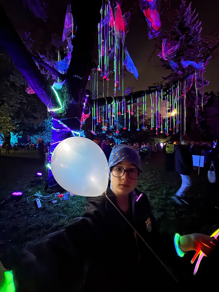 Mikołaj Sochacki - zdjęcie kolorowe drzewa Park Staromiejski, chłopiec z świecącym balonem w rękach na tle drzewa